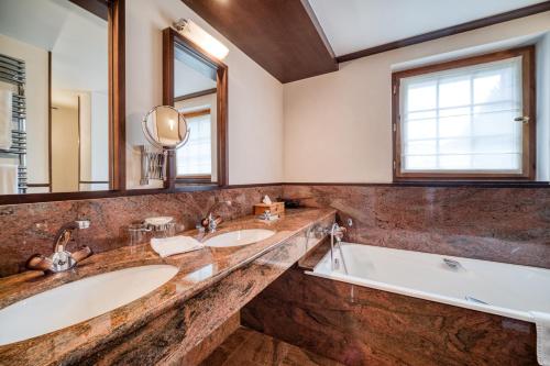 a bathroom with two sinks and a tub and a large mirror at Auberge du Bois Prin in Chamonix