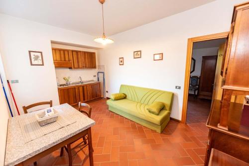 a living room with a green couch and a kitchen at Abadia Farneto in Gubbio