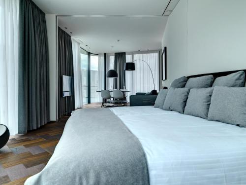 a bedroom with a large white bed and a living room at Hotel Gartner in Tirolo