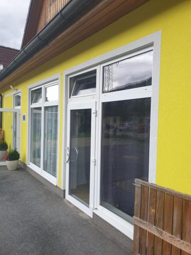 a yellow building with sliding glass doors on it at Apartment Hofacker in Pernegg an der Mur