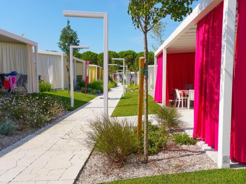 a walkway between two houses with pink curtains at Portofelice Camping Village in Eraclea Mare