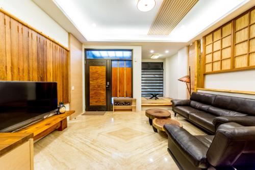 a living room with a leather couch and a flat screen tv at 榛品包棟民宿 in Puli