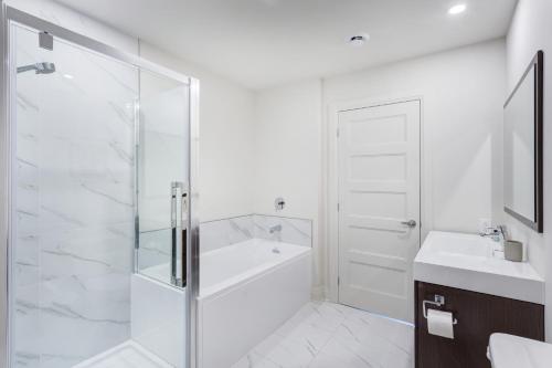 a bathroom with a glass shower and a sink at L'Equinox Modern Apartments by Corporate Stays in Laval