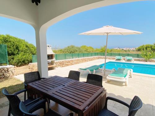 a patio with a table and chairs and a pool at Villa ELSIE in Arenal d'en Castell