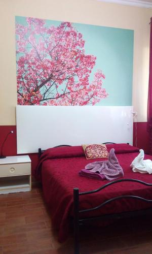 a bedroom with a red bed with a painting on the wall at Villa Morgante B&B in Pedara