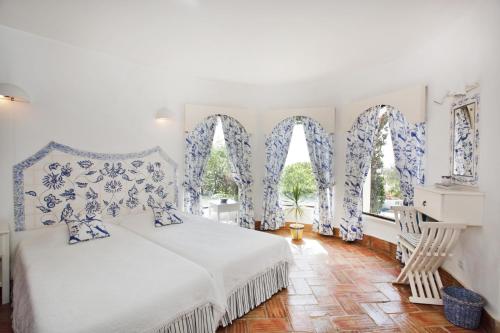 a bedroom with a white bed and two windows at Casa dos Gemeos in Luz