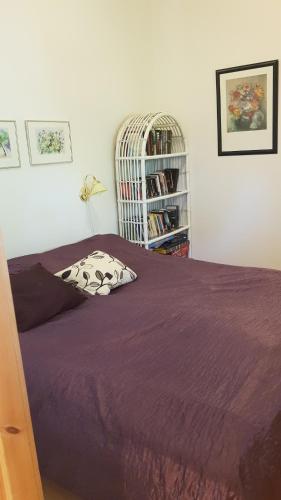 a bedroom with a purple bed and a book shelf at Mårbys Gästrum in Mårby