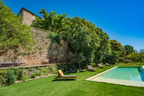un jardin avec une piscine et un mur en pierre dans l'établissement Location prestige 450 m2 dans Château en Provence, à Brue-Auriac