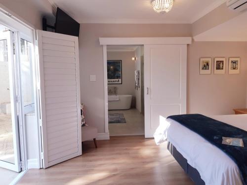 a bedroom with a bed and a bathroom with a tub at Amberhall Guesthouse in Johannesburg
