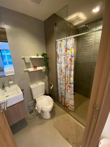 a bathroom with a toilet and a shower and a sink at Rain Cha-am Huahin in Cha Am