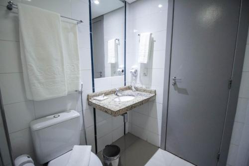 a white bathroom with a sink and a toilet at Oscar Hotel Executive in Porto Velho
