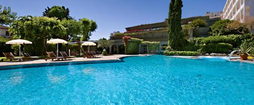 阿巴諾泰爾梅的住宿－Europa Terme Boutique Hotel，一个带椅子和遮阳伞的大型蓝色游泳池