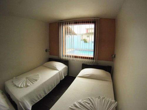two beds in a room with a window at Pousada do Albatroz in Cabo Frio
