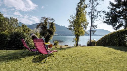 two chairs sitting on the grass near a lake at Haus Regina in Strobl