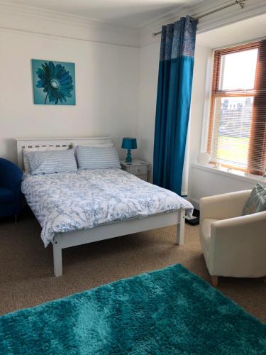 a bedroom with a bed with blue curtains and a couch at Rockvilla Guest House in Lerwick