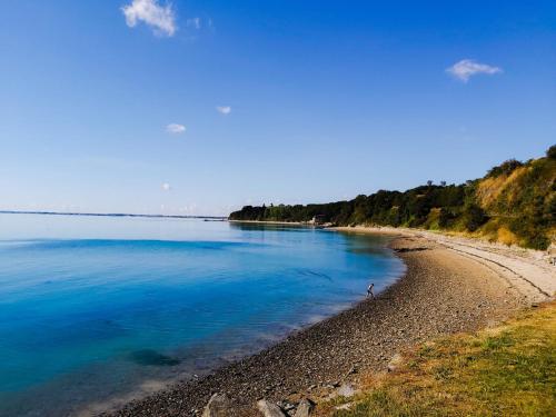 a beach with a person standing on the shore at Hotel La Voilerie Cancale bord de mer in Cancale