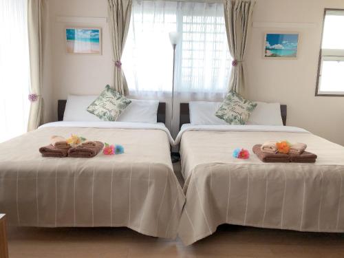 two beds with towels on them in a bedroom at TerraceRin YN22 in Tomigusuku