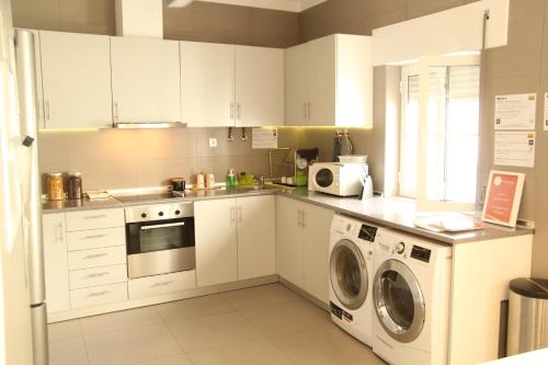 a kitchen with white cabinets and a washer and dryer at StayInn City - Évora in Évora