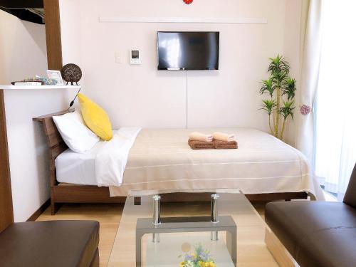 a bedroom with a bed with a tv on the wall at TerraceRin YN22 in Tomigusuku