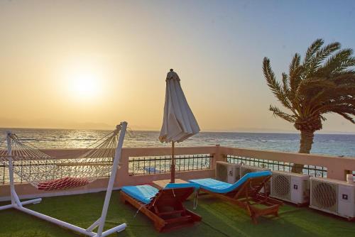 a balcony with a hammock and an umbrella and the ocean at Solaris in Dahab
