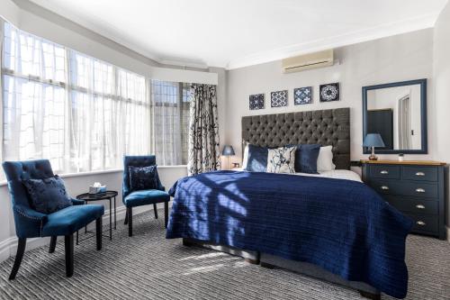 1 dormitorio con 1 cama azul y 2 sillas azules en Martel Guest House, en Londres