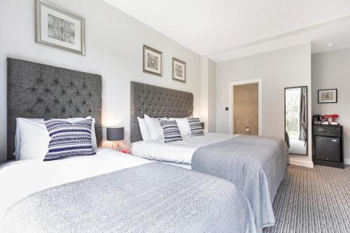 two beds in a bedroom with white walls at Martel Guest House in London