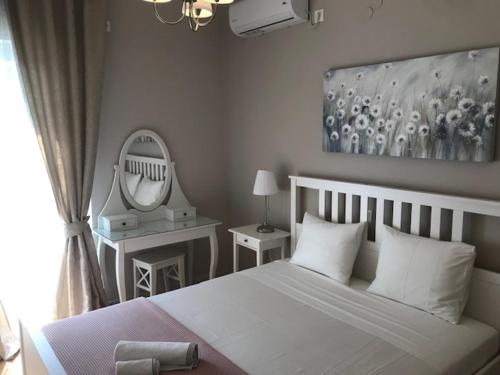 a bedroom with a white bed and a mirror at BALATSOURAS APARTMENT in Paleros