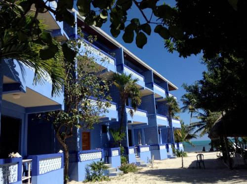 a blue building on the beach next to the ocean at Anchorage Beach Resort Caye Caulker in Caye Caulker