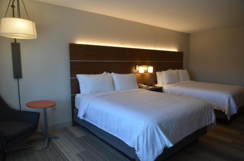 a hotel room with two beds and a chair at Holiday Inn Express Hotel & Suites Rochester by IHG in Rochester