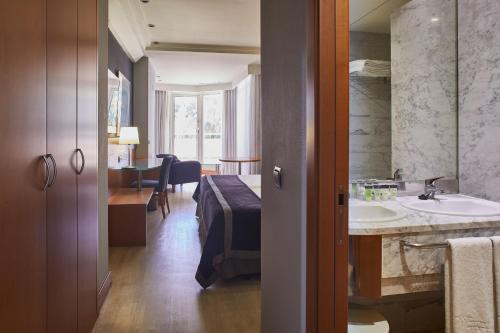 un bagno con lavandino e un letto in una camera di Silken Al-Andalus Palace a Siviglia