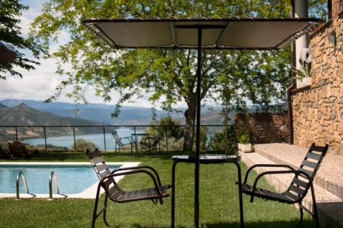 een tafel en stoelen onder een parasol naast een zwembad bij Casa Boumort in Sant Marti de Canals