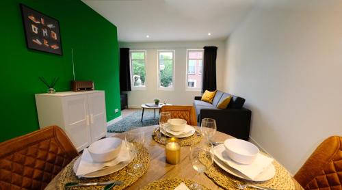 een eetkamer met een tafel en een groene muur bij Luxury 60m2 Apartment with 20m2 Private Terrace in Eindhoven
