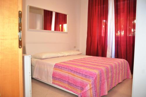 a small bedroom with a bed with red curtains at Via Battisti 231 1 in Pietra Ligure