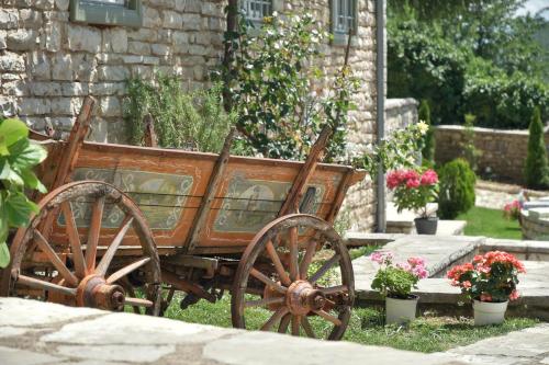 an old wooden cart sitting in the grass with flowers at Ameliko Zagori in Ano Pedina