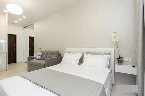 een witte slaapkamer met een bed en een bank bij Современная квартира в Аркадии с балконом и видом на море in Odessa