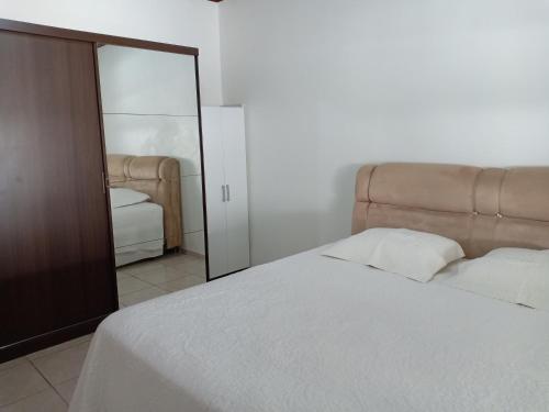 1 dormitorio con cama blanca y espejo en Casa Aconchego Fóz, en Foz do Iguaçu