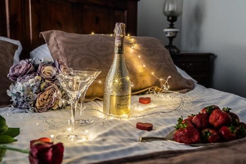 Una botella de champán y copas en una cama con fresas. en Willa Azja SPA & Wellness, en Zakopane