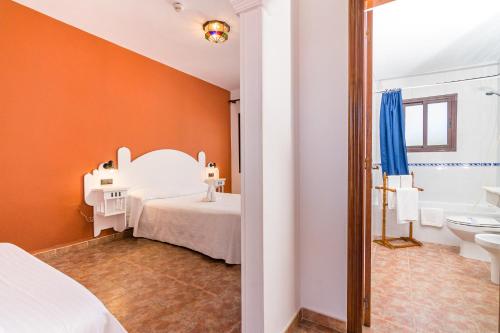 a bedroom with a white bed and a bathroom at Hostal Alhambra in Zahora