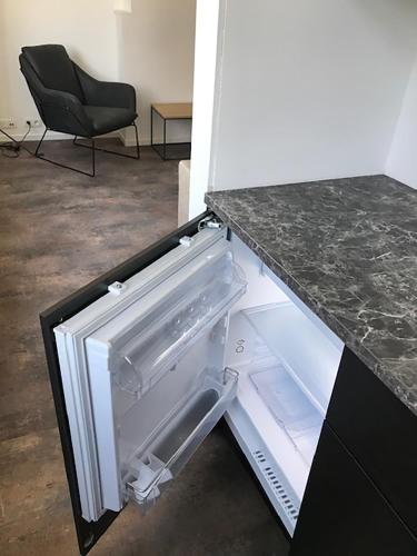 an empty refrigerator with its door open next to a chair at Brussel House Basilic in Brussels
