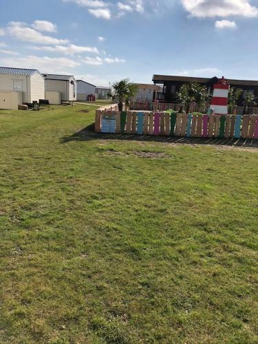 a fence in a field of grass with a building at MOONSTONE Lymington in Leysdown-on-Sea