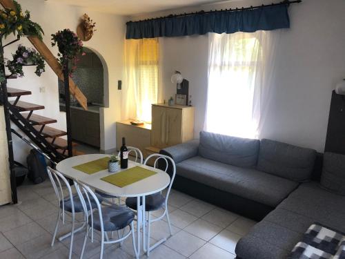 salon z kanapą, stołem i krzesłami w obiekcie Anita Apartmanház w mieście Orfű