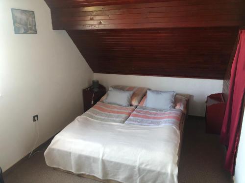 1 dormitorio pequeño con 1 cama y techo de madera en Anita Apartmanház, en Orfű
