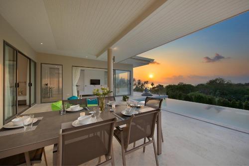 a dining room with a table and chairs on a balcony at Samui Bayside Luxury Villas in Choeng Mon Beach