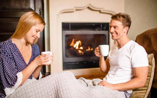 a man and woman sitting in front of a fireplace drinking coffee at Roman Spa Resort in Calistoga