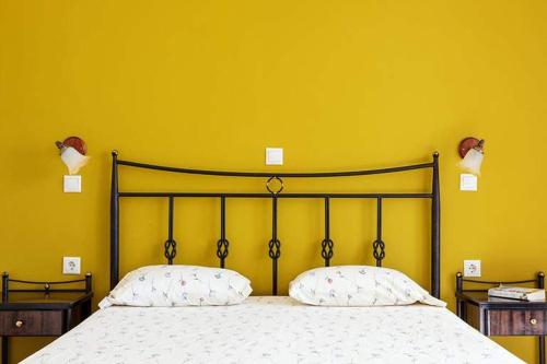 1 cama con 2 almohadas en un dormitorio amarillo en Sea Melody, en Lefkos Karpathou