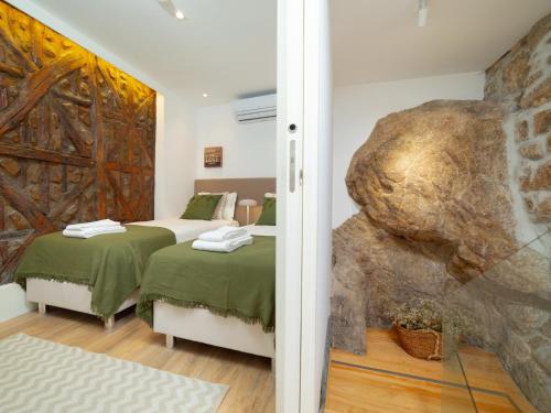 a bedroom with two beds and a stone wall at Ponte D Luis I Apartments in Porto