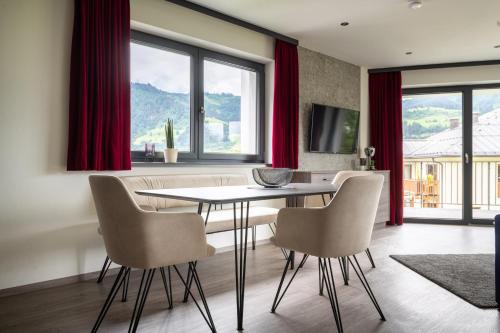 a dining room with a table and chairs and red curtains at Freiraum 9 Living Apartment in Sankt Johann im Pongau