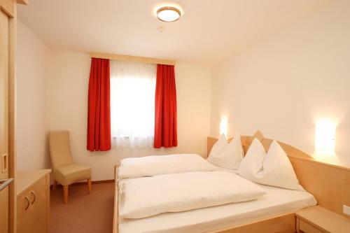 a bedroom with a bed and a window with red curtains at Hotel Römerhof in Fusch an der Glocknerstraße