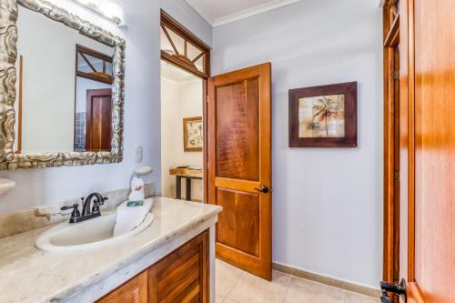 een badkamer met een wastafel en een spiegel bij La Paloma Blanca in Jacó