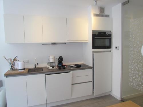 a white kitchen with white cabinets and a sink at Les Courlis 0203 in De Panne